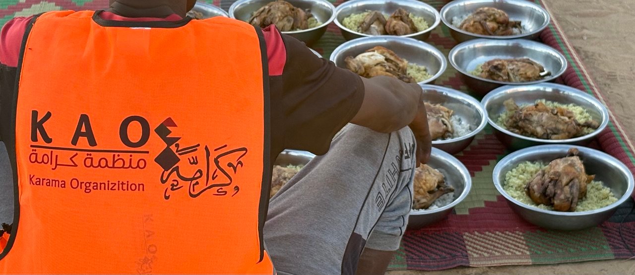 A Karama volunteer distributing meals under the community-kitchen (Takaya) program